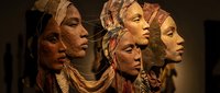 Ancient tribal masks with weathered faces and traditional headdresses displayed in museum exhibition showcasing indigenous cultural artifacts and ceremonial art.