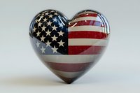 Glossy heart shape decorated with American flag pattern featuring stars and stripes in red, white, and blue colors on neutral background, patriotic symbol concept.