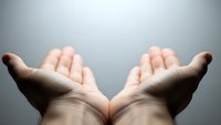 Open cupped hands gesture showing palms up in receiving position against neutral background for spiritual and wellness concepts.