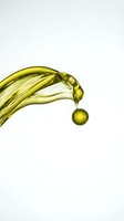 Golden oil dripping from curved stream against white background, isolated for skincare, cosmetics, and wellness product design use.