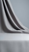 Elegant gray silk fabric draping gracefully with soft folds and smooth texture creating luxurious backdrop for fashion and interior design projects.