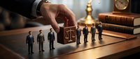 Business hand selecting professional candidate from group of miniature businesspeople on wooden desk with legal scales and law books in corporate office.