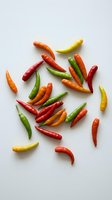 Colorful hot chili peppers scattered on white background. Fresh spicy vegetables in red, green, orange and yellow colors for cooking and culinary projects.