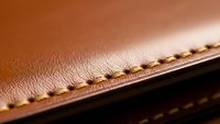 Brown leather material with detailed stitching showcasing craftsmanship and texture for luxury goods, fashion accessories, and artisan products.