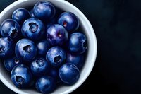 Fresh ripe blueberries in white ceramic bowl on dark background. Healthy organic superfood berries for breakfast, smoothies and desserts.