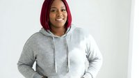 Young African American woman with red hair wearing gray hoodie smiling confidently against white background for lifestyle and fashion content.