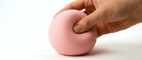 Hand holding pink stress ball for relaxation and exercise therapy on white background isolated for design use.