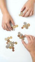 Multiple hands arranging various coins on white background, representing financial management, savings, budgeting and money distribution concepts for business and personal finance.