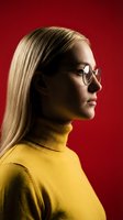 Young blonde woman in yellow turtleneck sweater and round glasses profile portrait against red background with dramatic lighting for fashion concepts.
