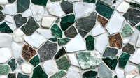Mosaic pattern of irregular green, white, and brown stone fragments creating abstract geometric design. Decorative surface texture for interior backgrounds.
