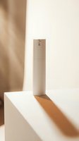 Minimalist beige cosmetic spray bottle on white platform with warm natural lighting and soft shadows for skincare beauty product mockup.