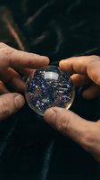 Close-up of hands holding a crystal sphere containing a glowing galaxy with stars and nebula, symbolizing cosmic wonder and universe exploration for astronomy and science concepts.