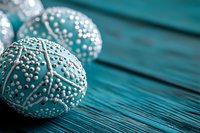 Decorative turquoise Easter eggs with white pearl beading pattern on wooden background. Selective focus creates artistic depth for seasonal holiday designs.