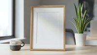 Empty wooden picture frame mockup on desk with coffee cup and plant for home decor and office design projects.