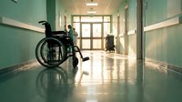 Empty wheelchair in hospital corridor with green walls and polished floors. Healthcare facility interior for medical rehabilitation and patient care concepts.