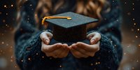 Hands holding graduation cap with golden tassel against dark background with bokeh lights, symbolizing academic achievement and educational success.
