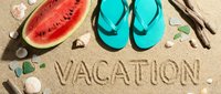 Vacation written in sand on sunny beach with teal flip flops, fresh watermelon slice, seashells, and driftwood for summer travel concepts.