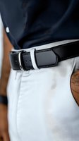 Close-up view of classic black leather belt with silver buckle on white pants, showing elegant contrast and refined style detail for fashion and accessories marketing.