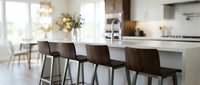 Modern kitchen island with dark wooden bar stools, white countertop, and bright natural light from windows. Contemporary dining and cooking space for home design and interior decoration projects.