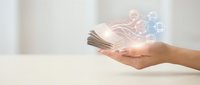 Hand holding stack of banknotes with glowing digital network icons and light effects, representing financial technology, digital payments, money transfer, and blockchain innovation.