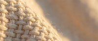 Closeup of woven beige fabric texture with soft natural lighting, suitable for textile, fashion, and design backgrounds.
