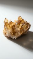 Cluster of golden citrine quartz crystals with translucent faceted points on white background, suitable for mineral, geology, and wellness content.