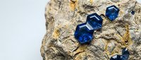 Blue sapphire gemstones embedded in natural rough rock matrix showing crystalline formation and mineral deposits for jewelry and geological study.