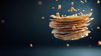 Levitating stack of crispy potato chips with flying crumbs and salt particles against dark background, dynamic food photography composition.