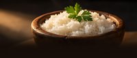 Steamed white rice in wooden bowl garnished with fresh parsley on dark background. Healthy grain side dish for Asian cuisine and comfort food meals.