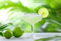 Fresh lime daiquiri cocktail garnished with citrus slice on bright green tropical background, served in classic coupe glass with fresh ingredients.