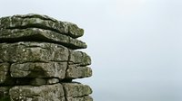 Stacked stone rocks with lichen and moss growth against overcast sky, representing geology, nature, and outdoor landscape elements.