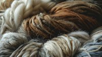 Luxurious natural wool and feather textures in earthy brown, cream and gray tones create soft layered pattern for textile and craft backgrounds.