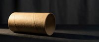 Empty brown cardboard tube roll lying on dark surface with dramatic lighting and shadows for packaging design and craft projects.