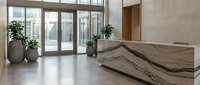 Modern office lobby with marble reception desk and large windows overlooking urban cityscape. Contemporary corporate interior design with plants and natural light.