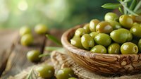 Fresh green olives in rustic wooden bowl on burlap cloth against blurred natural background, selective focus creates appetizing Mediterranean mood.