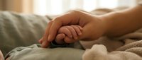 Newborn baby holding mother's finger on soft blanket, tender moment of love and family bond in warm light.