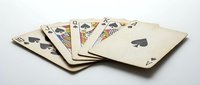 Vintage playing cards fanned out on white surface, showing spades suit with aged cream-colored card backs and worn edges, suitable for gambling, game design, and retro themed projects.