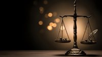 Bronze scales of justice on wooden surface with warm bokeh lighting background for legal and law firm presentations.