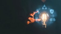 Businessman hand touching glowing lightbulb with digital icons for innovation, technology, and security solutions in business strategy and development.