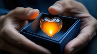 Glowing heart-shaped glass object held gently in hands against dark background, emanating warm orange light. Romantic mood lighting creates intimate atmosphere.
