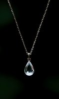 Elegant silver chain necklace with crystal teardrop pendant on dark background for luxury jewelry and fashion accessories.
