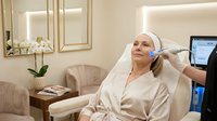 Middle-aged Caucasian woman receiving professional facial treatment in luxury spa clinic with modern equipment and elegant interior design.