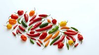 Fresh red, orange, and yellow chili peppers arranged on white background, isolated produce for culinary, cooking, and food design projects.