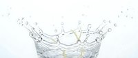 Clear water splash with dynamic droplets and crown formation against white background for refreshing beverage and purity concepts in commercial design.
