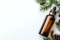 Brown glass dropper bottle with pine branches and cones on white background. Natural aromatherapy and wellness concept with copy space for seasonal design.