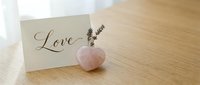 Rose quartz heart crystal with dried lavender and love greeting card on wooden table, romantic Valentine day decor concept.