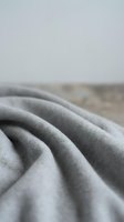 Soft gray fabric with elegant folds and drapes creating luxurious textile texture for fashion design and interior decoration projects.