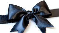 Elegant black satin bow with shiny texture and symmetrical loops on dark background, isolated for design projects and decorative elements.