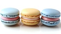 Three colorful French macarons with cream filling isolated on white background for bakery menu design and confectionery advertising materials.