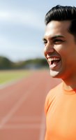 Young man with dark hair and olive skin tone wearing orange athletic shirt, smiling at running track. Suitable for sports, fitness, wellness, and lifestyle marketing.